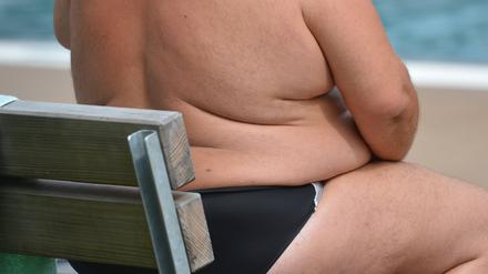 Ein übergewichtiger Mensch sitzt in einem Freibad in Stuttgart.