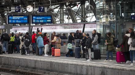 Bahnreisende warten auf dem Bahnsteig auf die Einfahrt des Zuges im Kölner Hauptbahnhof. 
