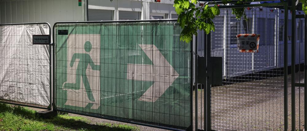 Ein Transparent mit dem Symbol für den Fluchtweg hängt vor Wohncontainer der kommunalen Erstaufnahmeeinrichtung in Köln-Zollstock.