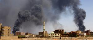 FILE PHOTO: A man walks while smoke rises above buildings after aerial bombardment, during clashes between the paramilitary Rapid Support Forces and the army in Khartoum North, Sudan, May 1, 2023. REUTERS/Mohamed Nureldin Abdallah/File Photo