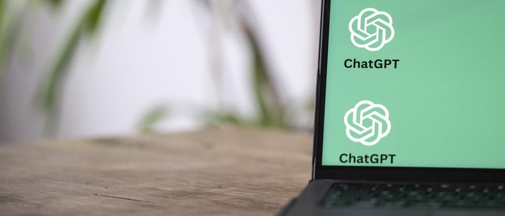 Die ChatGTP-Logos auf dem Monitor des Laptops zeigen, dass hier mit Künstlicher Intelligenz gearbeitet wird.
