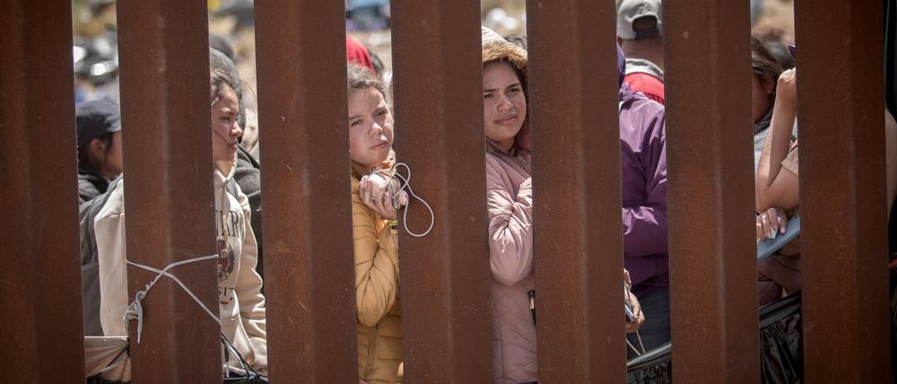 Frauen stehen hinter der Grenzmauer zwischen Mexiko und USA und hoffen darauf, in die USA einreisen zu können.