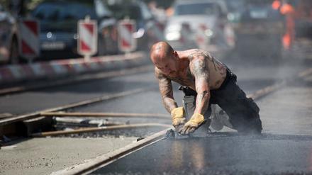 Bei sommerlichen Temperaturen arbeitet Axel mit heißem Teer an Gleisen der Straßenbahnlinie 50 am 26.05.2014 in Berlin-Pankow. Foto: Jörg Carstensen/dpa +++(c) dpa - Bildfunk+++