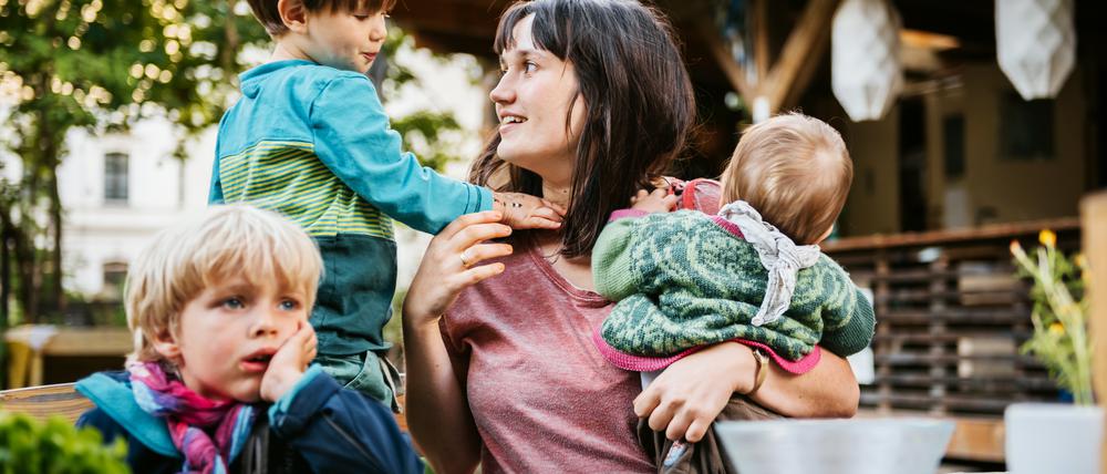 Young mother with children sitting in a community garden on a table