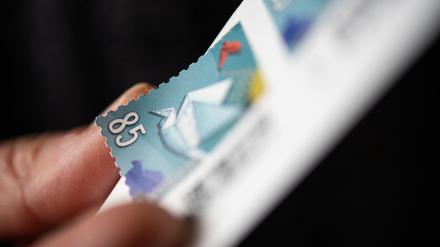 Eine Frau löst eine 85 Cent Briefmarke von einem Bogen.