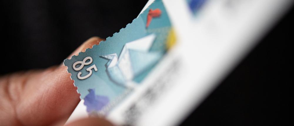 Eine Frau löst eine 85 Cent Briefmarke von einem Bogen.