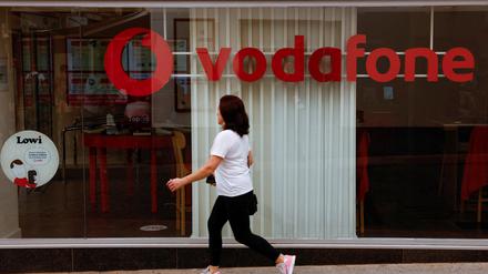 Eine Frau läuft an einem Geschäft von Vodafone vorbei.