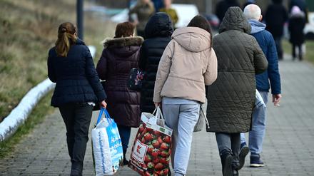 Ukrainische Flüchtlinge gehen nach ihrer Registrierung in der Orangerie der Biosphäre zur Straße.