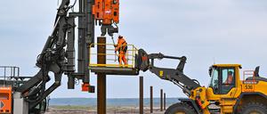 Sogenannte Dalben, Stahlrohre als Befestigungspunkt, werden beim Bau einer schwimmenden Photovoltaik-Anlage in die Erde auf dem Gelände des künftigen Ostsees gerammt.