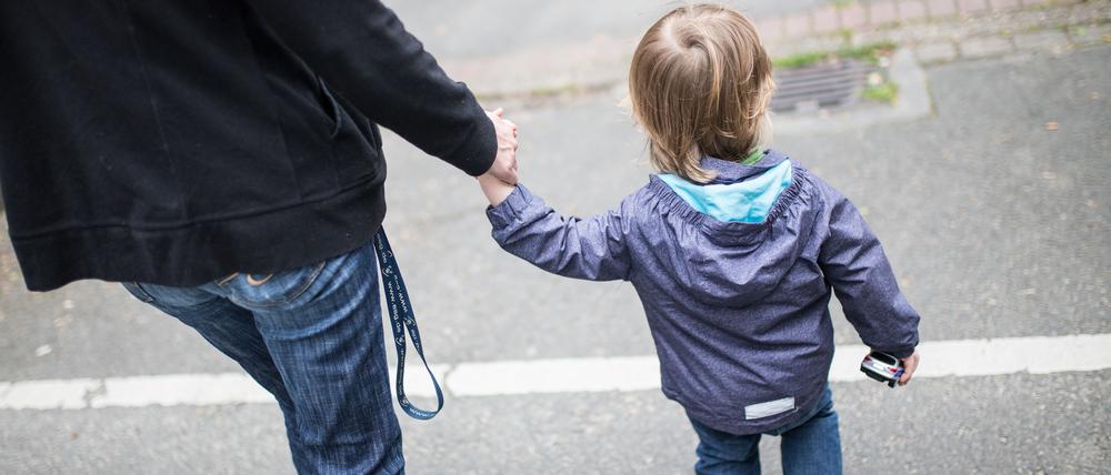Eine Mutter hält ihren Sohn an der Hand.