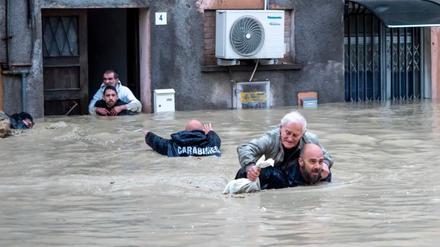 Carabinieri tragen Anwohner huckepack durch die überschwemmten Straßen. Die italienischen Regionen Emilia-Romagna und die Marken werden weiter von schweren Unwettern heimgesucht.