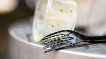 Plastikgeschirr liegt auf einem Mülleimer.