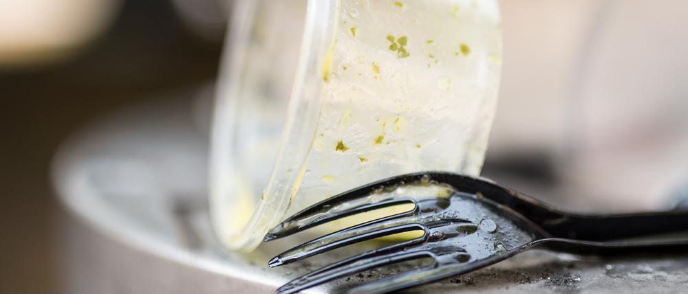 Plastikgeschirr liegt auf einem Mülleimer.