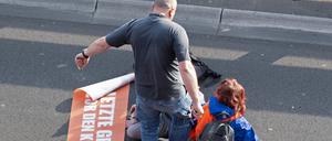 Bei einer Blockade der Gruppe Letzte Generation auf der Stadtautobahn unweit des Kurfürstendamms tritt ein Mann gegen einen Aktivisten.