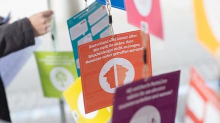 Eine Jugendliche steht an einem Wahlstand für die U-18-Wahl neben Zetteln mit Informationen zu den Parteien.