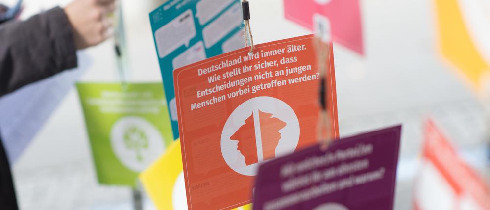Eine Jugendliche steht an einem Wahlstand für die U-18-Wahl neben Zetteln mit Informationen zu den Parteien.