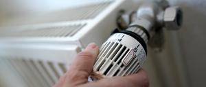 Eine Frau dreht an einem Heizungsthermostat.