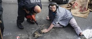 Wenn die Polizei zur Hilti greifen muss: Ein Polizei stemmt Asphalt aus der Straße, an den sich ein Aktivist geklebt hat.