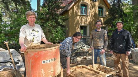Kristina Gummlich (l) und Christian Bott (2.v.r) stehen zusammen mit den Helfern Agata Kopka und Jason Adkins am Lehmmischer auf der Baustelle für ihr neues Eigenheim. Ein auffälliges braunes Haus aus Lehm wächst im Bernauer Ortsteil Birkholzaue (Barnim) und zieht immer wieder Schaulustige an. 