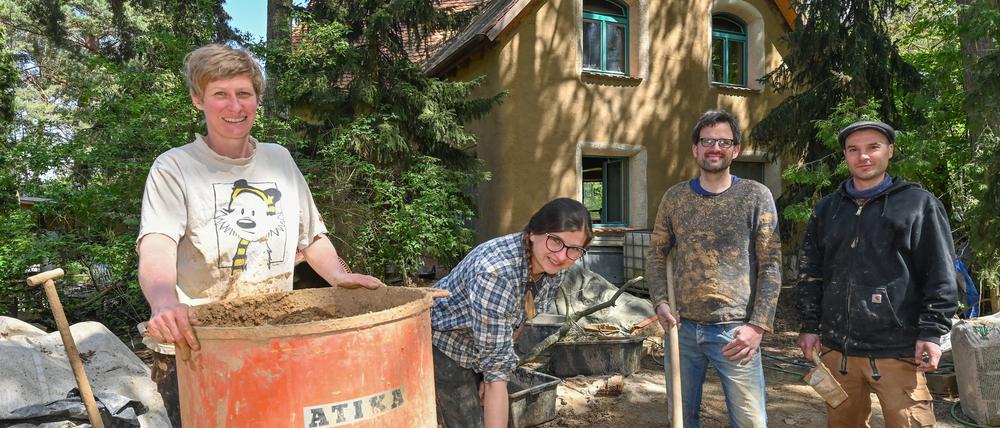 Kristina Gummlich (l) und Christian Bott (2.v.r) stehen zusammen mit den Helfern Agata Kopka und Jason Adkins am Lehmmischer auf der Baustelle für ihr neues Eigenheim. Ein auffälliges braunes Haus aus Lehm wächst im Bernauer Ortsteil Birkholzaue (Barnim) und zieht immer wieder Schaulustige an. 