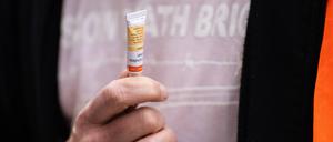 Ein Mitglied der „Letzten Generation“ hält eine Tube Sekundenkleber in der Hand.