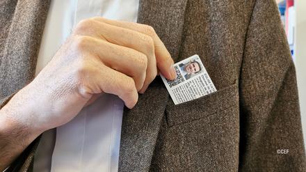 Ein Geistlicher zieht den neuen französischen Priesterausweis aus einer Westentasche.
