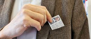 Ein Geistlicher zieht den neuen französischen Priesterausweis aus einer Westentasche.