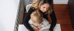 Mit Kleinkind hinterm Laptop? Selbstständige müssen oft früher in den Beruf zurückkehren als abhängig Beschäftigte.