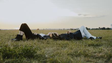 Female friends lying down on grass in park