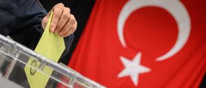 Ein Wähler wirft seinen Wahlumschlag in eine Urne in einem Wahllokal für die türkische Präsidentschaftswahl in der Messe Hannover.