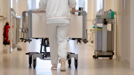 Eine Krankenpflegerin schiebt ein Bett über einen Flur. 