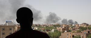 Ein Mann blickt auf die Stadt Khartum, wo schwarzer Rauch aufsteigt.