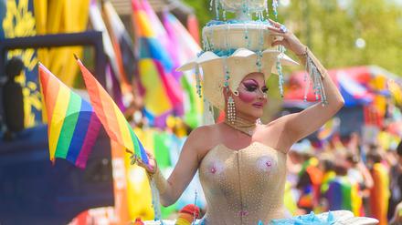 20. Mai 2023, Dessau, Sachsen-Anhalt: Eine Person in einem ausgefallenen Kostüm schwenkt bei der Parade zum Christopher Street Day eine Regenbogenflagge.