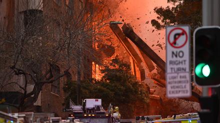 Gebäudeteile fallen hinab bei einem Feuer, das in einem mehrstöckigen Gebäude in der Innenstadt von Sydney ausgebrochen ist. 