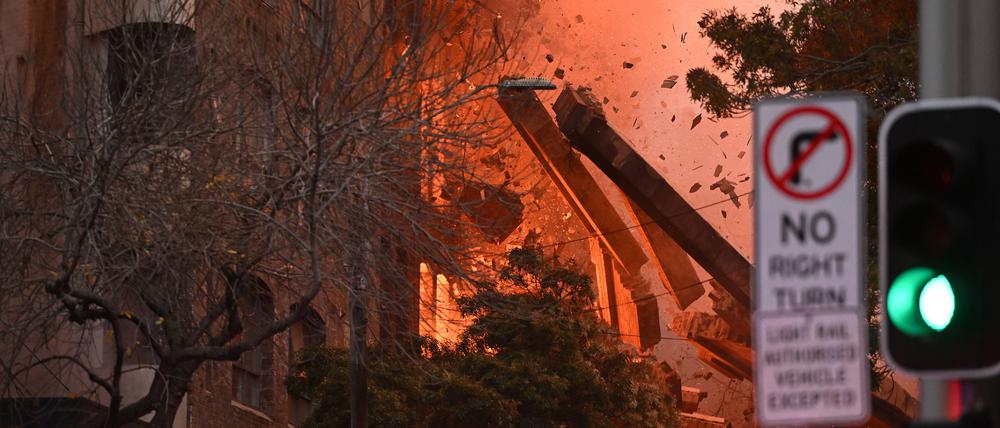 Gebäudeteile fallen hinab bei einem Feuer, das in einem mehrstöckigen Gebäude in der Innenstadt von Sydney ausgebrochen ist.