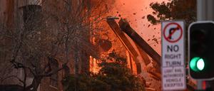 Gebäudeteile fallen hinab bei einem Feuer, das in einem mehrstöckigen Gebäude in der Innenstadt von Sydney ausgebrochen ist. 