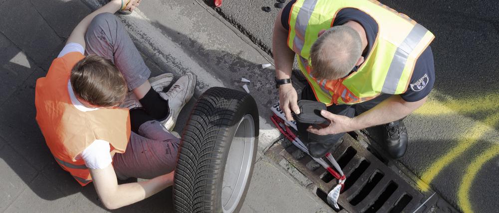 Ein Aktivist sitzt samt losgelösten Rad, an dem er festgeklebt ist, bei einer Blockade der Letzten Generation auf der Autobahn 100.