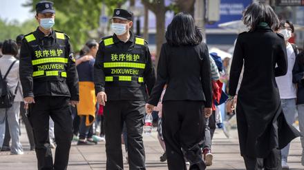 Sicherheitsbeamte mit Gesichtsmasken patrouillieren entlang einer Einkaufsstraße in Peking.