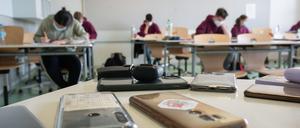 Ausgeschaltete Smartphones liegen in einem Klassenzimmer.