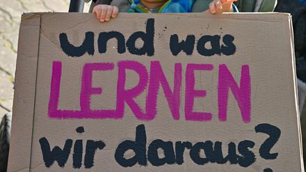 Ein Schild mit der Aufschrift «und was lernen wir daraus?» hält ein Kleinkind in seinem Wagen bei der Demonstration «Vielfalt statt Einfalt – Schule ohne Diskriminierung» vor dem Schulamt in Cottbus in seinen Händen.