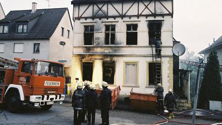Feuerwehrleute stehen vor dem ausgebrannten Haus der türkischen Familie Genc.