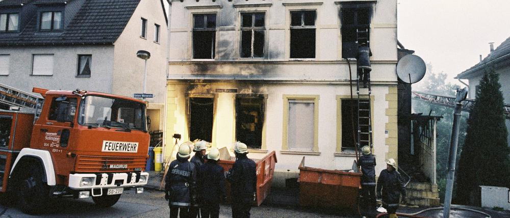 Feuerwehrleute stehen vor dem ausgebrannten Haus der türkischen Familie Genc.