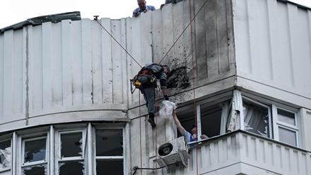 Ein Spezialist inspiziert die beschädigte Fassade eines mehrstöckigen Wohnhauses nach einem Drohnenangriff in Moskau: