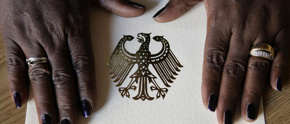 Die Hände einer Frau liegen auf der Einbürgerungsurkunde der Bundesrepublik Deutschland.