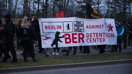 Teilnehmer einer Demonstration gegen den Bau eines geplanten Abschiebezentrums am Flughafen Berlin Brandenburg BER tragen Transparente. 