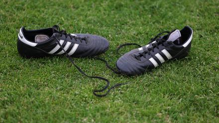 Drei Streifen. Fußballschuhe liegen am Spielfeldrand. 
