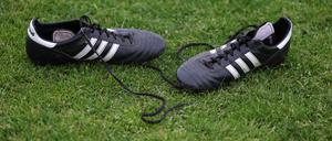 Drei Streifen. Fußballschuhe liegen am Spielfeldrand.