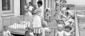In der Neustadt von Hoyerswerda sind 1963 die Kleinen aus einer Kinderkrippe mit ihren Erzieherinnen auf der Terrasse.