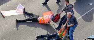 Aufgebrachte Verkehrsteilnehmer, die durch die Aktivisten aufgehalten werden, versuchen die Protestler von der Straße zu ziehen.