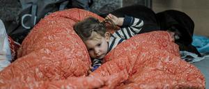 Ein kleines Mädchen liegt unter einer Decke in einer Metrostation in Charkiw. 